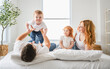 © Louis-Photo - happy family mother, father and children having fun in bed in bedroom at home