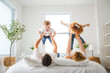 © Louis-Photo - happy family mother, father and children having fun in bed in bedroom at home