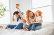 © Louis-Photo - happy family mother, father and children having fun in bed in bedroom at home