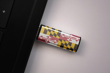 Wall Mural - usb flash drive in notebook computer with the national flag of maryland state on gray background.