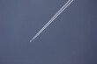 White contrails behind an airplane in a bright, cloudless sky