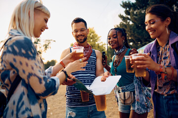 Wall Mural - Young happy friends drinking beer while attending open air music concert in summer.