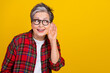 © deagreez - Photo of cheerful grandmother arm near ear listen look eavesdrop empty space conversation isolated on yellow color background