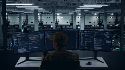 Back View Of Asian Military Drinking Coffee And Using Computer To Write Code With Multiple Screens In Data Center