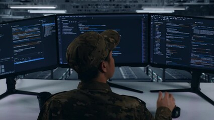 Back View Of Asian Military Thinking About Something While Write Code With Multiple Computer Screens In Data Center