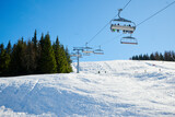 Fototapeta  - Wyciąg narciarski, kanapa, kolej linowa w ośrodku narciarskim w górach. śnieg, zima, słońce. Pod światło.