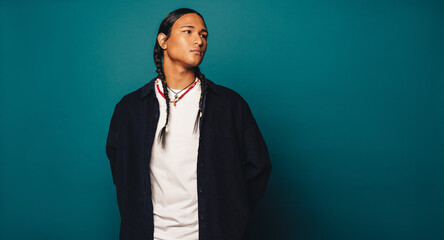 Wall Mural - Native American man with braided hair and cultural jewelry standing in a studio