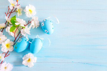 Wall Mural - Happy Easter holidays greeting card; Artificial branch with white blossom and blue easter eggs on a blue paint wooden background; copy space