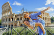 Happy couple - woman and man tourist have fun on vacation at Rome Colosseum