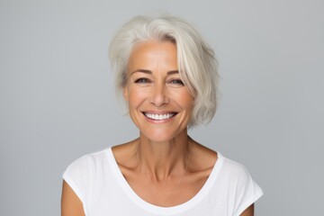 Wall Mural - Portrait of beautiful mature woman smiling at camera, over grey background