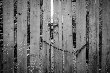 Weathered wooden gate locked with hasp and chain