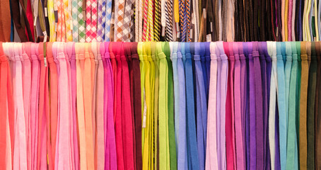 Poster - A row of colorful strings laces are displayed in a store. The colors are bright and vibrant, creating a cheerful and lively atmosphere. The strings are arranged in a way that showcases their variety