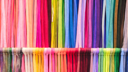 Leinwandbilder - A row of colorful strings laces are displayed in a store. The colors are bright and vibrant, creating a cheerful and lively atmosphere. The strings are arranged in a way that showcases their variety
