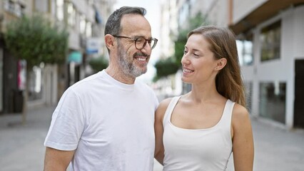 Wall Mural - Father and daughter, standing together on a sunny city street, looking into each other's eyes, smiling with confidence, and radiating joy and love