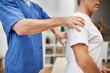 © LIGHTFIELD STUDIOS - cropped view of dedicated doctor in blue robe helping his mature patient to rehabilitate in ward