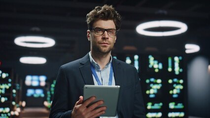 Smiling software engineer holding tablet computer in data center room closeup