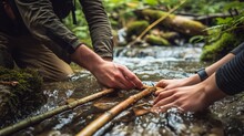A Close-up Of Hands Assembling A Makeshift Bridge Across A Stream During A Thrilling Adventure With Friends.