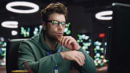 Focused scripter looking computer typing keyboard at night datacenter closeup