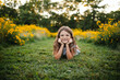 © Maria Manco/Stocksy - Preteen smiles at camera in wildflower field