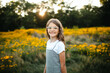 © Maria Manco/Stocksy - Preteen smiles at camera in wildflower field
