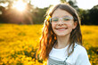© Maria Manco/Stocksy - Preteen smiles at camera in wildflower field