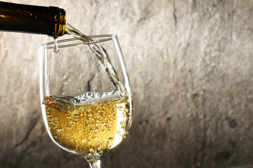 Sticker - Pouring white wine into glass against grey background, closeup. Space for text