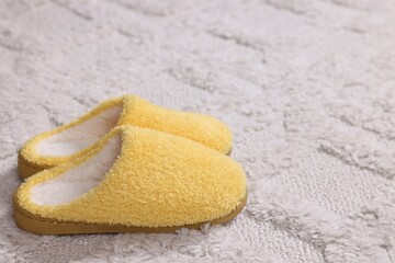 Wall Mural - Yellow soft slippers on light carpet, closeup. Space for text