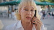 © stockbusters - Serious pensioner talking mobile phone on street close up. Worried lady calling
