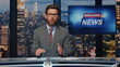 © stockbusters - Bearded newscaster ending program in evening newsroom studio. Late breaking news
