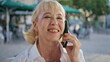 © stockbusters - Cheerful pensioner enjoy call cell phone on urban street close up. Woman talking