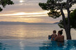 Loving mother with small toddler swimming in infinity pool during sunset at Makarska Riviera, Split-Dalmatia, Croatia, Europe. Adriatic Mediterranean Sea. Dreamlike atmosphere. Family vacation concept