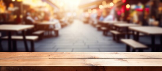 A wooden table stands on a hardwood floor in a restaurant, surrounded by blurry tables and benches. The building has a warm wood stain on its planks