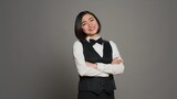 Fototapeta Tulipany - Asian receptionist posing with arms crossed on camera, feeling confident and professional in a formal suit and tie. Woman with front desk staff occupation, greeting guests in studio. Camera A.
