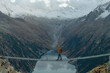 © Anna Tsukanova/Stocksy - Man passing the bridge above the lake in Alps