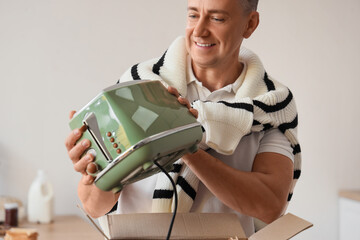 Canvas Print - Middle-aged man with new toaster in kitchen