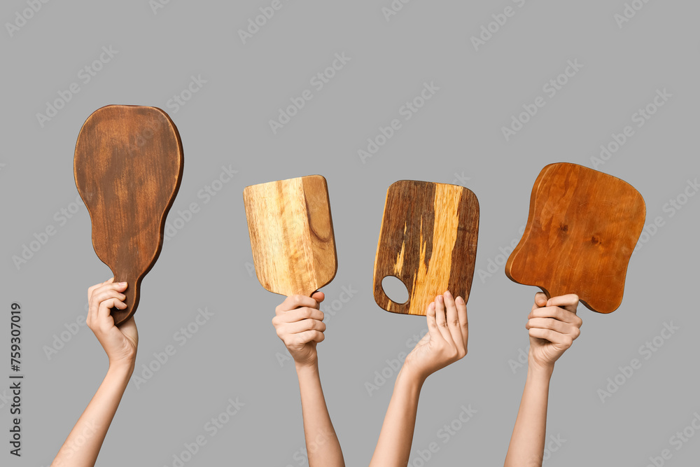 Female hands with wooden cutting boards on grey background