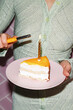 © Danil Nevsky/Stocksy - Crop woman lighting candle on piece of birthday cake