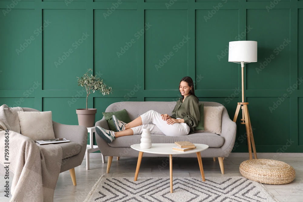 Beautiful woman resting on grey sofa in living room