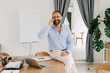 © Mihajlo Ckovric/Stocksy - Portrait of adult businessman using smartphone in office