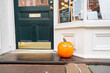 © Jessica Klaus/Stocksy - Pumpkin sitting on the stoop of a business door.