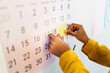 © Studio Marmellata/Stocksy - Crop executive sticking note on calendar at work