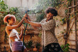 © Lucas Ottone/Stocksy - Black couple teasing each other playing with a water hose in summer
