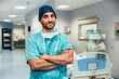 © VICTOR TORRES/Stocksy - Smiling male doctor with arms crossed standing in clinic