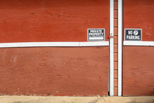 A couple no parking signs attached to red garage doors