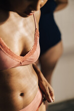 cropped image of a woman’s torso, wears a pale pink lingerie.