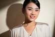 © Marc Tran/Stocksy - Smiling young beautiful Asian businesswoman in focus light