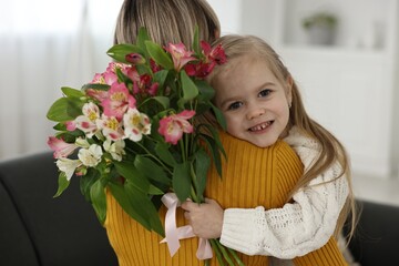 Sticker - Little daughter congratulating her mom with bouquet of alstroemeria flowers at home. Happy Mother's Day