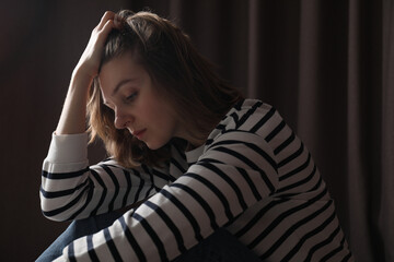 Poster - Sad young woman near closed curtains indoors