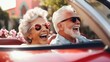 © JuliaDorian - Happy senior couple driving in a convertible with the top down on a sunny day