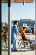 © BONNINSTUDIO/Stocksy - Wheelchair patient in hospital with male nurse assistant